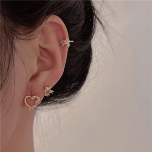 Detailed view of gold heart and star earrings set with blue and white zircons