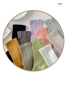 Flat lay of colorful mid-calf cotton socks in pastel tones on a white minimalist desk