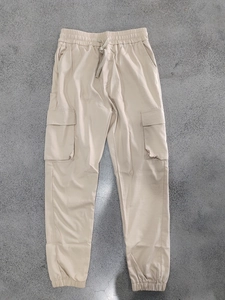 Close-up of beige cargo pants with elastic drawstring waist and flap pockets on fabric