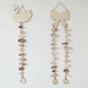 Wall-mounted wooden swan and bow hair clip organizers with pink ribbons and hair accessories