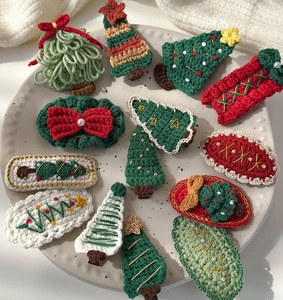 Flat lay of 12 handmade crochet Christmas hair clips with festive trees and wreaths