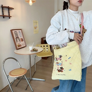 Detail of yellow quilted tote bag with cute dog embroidery and pink shoulder strap