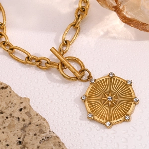 Macro shot of 18K gold plated starburst disc pendant with OT toggle clasp on white stone