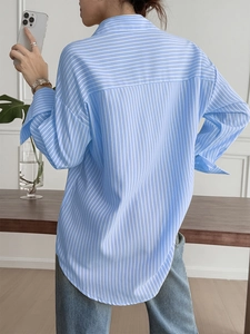 Rear view of women's blue striped shirt showing pleated back detail and loose fit design