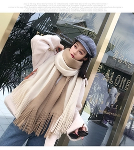 Detail of warm color-block tassel scarf paired with a grey plaid newsboy cap on model