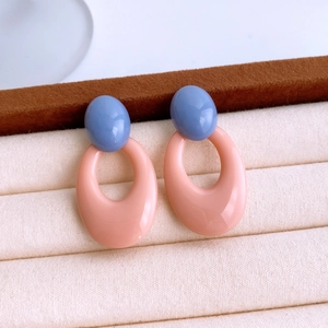 Macro view of blue and pink acrylic earrings showcased on beige velvet display