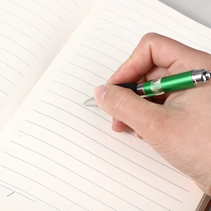 Close-up of a retractable ballpoint pen writing on cream-colored lined notebook paper