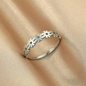Detailed close-up of a silver stainless steel daisy flower ring on elegant champagne satin
