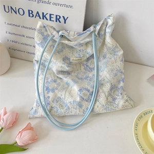 Detailed shot of white lace tote bag with floral patterns and blue cord handles