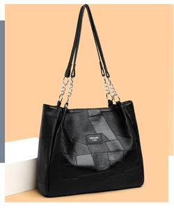 Detail of black tote bag featuring textured faux leather and metal chain straps