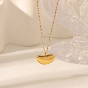 Close-up of polished gold bean pendant on a delicate stainless steel chain necklace