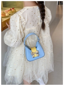 Detail of blue and yellow PU leather half-moon bag with bow and silver chain strap