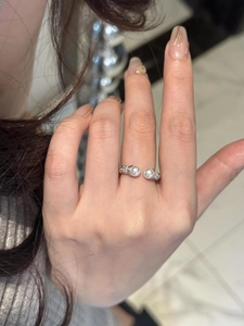 Detail view of adjustable silver twisted ring featuring two round pearls on a female hand