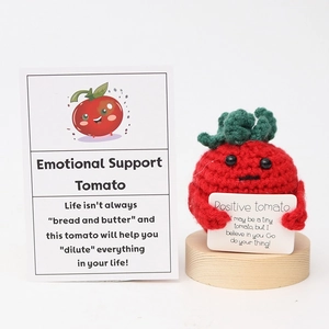 Detail of handmade crochet emotional support tomato with positive card on wooden base