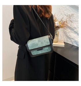 Detail of vintage green fabric shoulder bag with black leather trim worn by model
