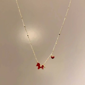 Gold plated necklace with red pony pendant and small heart detail on a gold chain