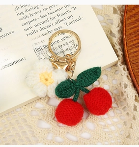 Detailed close-up of handmade woven cherry and flower keychain with golden metal ring