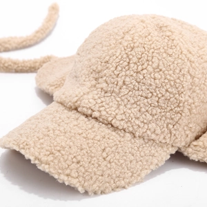 Detailed close-up showing soft beige lamb wool texture and warm earflaps of the baseball cap