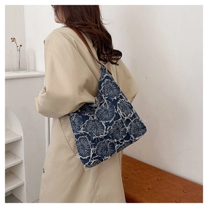 Close-up of vintage denim tote bag featuring frayed edges and floral embroidery detail