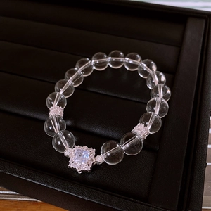 Macro detail of clear quartz bead bracelet with a square zircon centerpiece on black tray