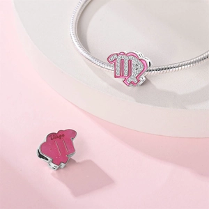 Macro view of Virgo zodiac charm with pink enamel and zircons on silver snake chain