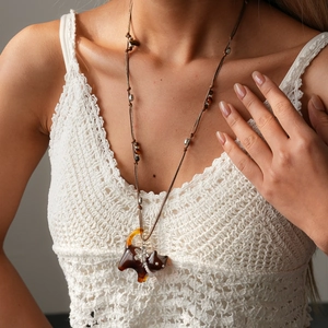 Detail of vintage cat sweater necklace with brown tiger eye resin on a woven top