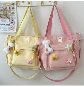 Detailed view of yellow and pink nylon tote bags with smiley patches and star charms