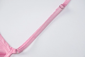 Close-up of pink silk-like dress strap with silver metal adjuster and precise stitching