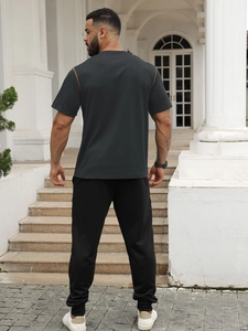 Back view of a casual gray t-shirt and black pants outfit set for men in an outdoor setting