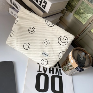 Close-up of cream corduroy storage bag with black smiley face print and woven label