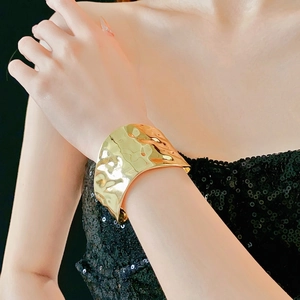 Bracelet manchette large doré à texture martelée irrégulière porté par un modèle