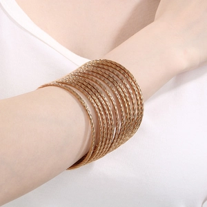 Detail of twisted multi-layer gold bangle bracelet with textured finish on wrist
