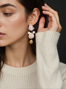 Detail of elegant gold drop earrings with natural sea shell, conch, and round pearl