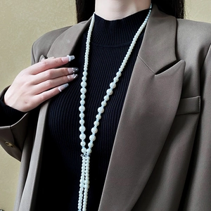 Detailed close-up of a long pearl necklace with diamond accents on an elegant model