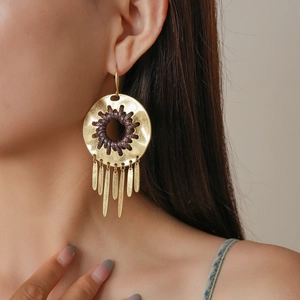 Detail of bohemian gold round earrings with brown woven texture and long metal tassels