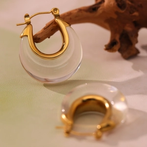 U-shaped stainless steel resin earrings in gold and clear tones on a wooden branch