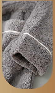 Detail of grey plush bathrobe sleeve with white piping and thick fleece texture