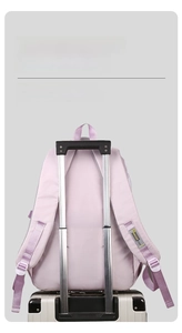 Close-up of purple backpack showing the luggage strap fixed on a white suitcase handle