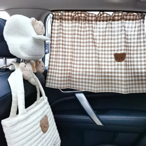 Close-up of brown plaid car curtain and quilted storage bag with cute plush bear decor