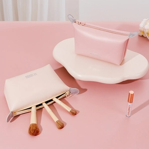 Waterproof PU leather dumpling makeup bags in pink and beige with embossed text