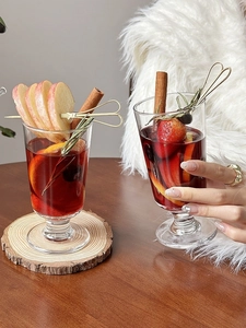 Close-up of winter mulled wine in elegant glass with apple slices and cinnamon sticks