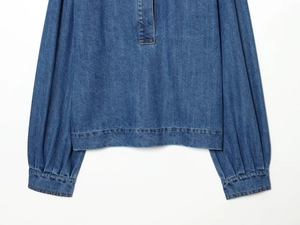 Détail d'une chemise en jean bleue avec poignets froncés et ourlet élastique ajusté