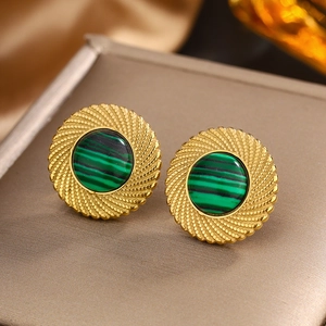 Vue macro de boucles d'oreilles dorées vintage avec incrustation verte sur métal brossé