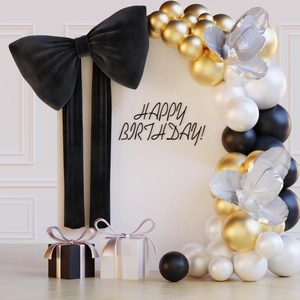 Detail of giant black velvet bow and elegant gold black white balloon arch for party decor