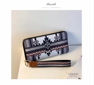 Close-up of geometric tribal print long wallet with gold zipper and wrist strap