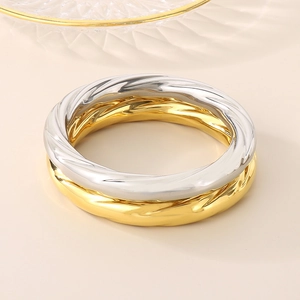 Detailed view of two-tone twisted bangles in gold and silver finish with metallic shine