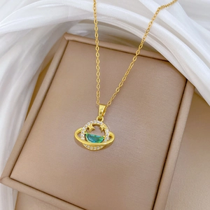 Detail of gold planet necklace with teal crescent stone and crystals on beige box