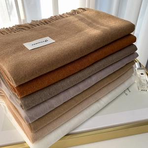 Stack of colorful cashmere scarves with tassels in camel, rust red and grey tones