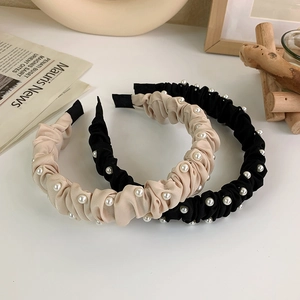 Dettaglio di cerchietti in tessuto plissettato beige e nero con eleganti perle