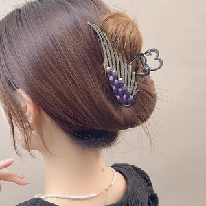 Macro detail of purple angel wing hair claw with rhinestones in a sleek bun hairstyle